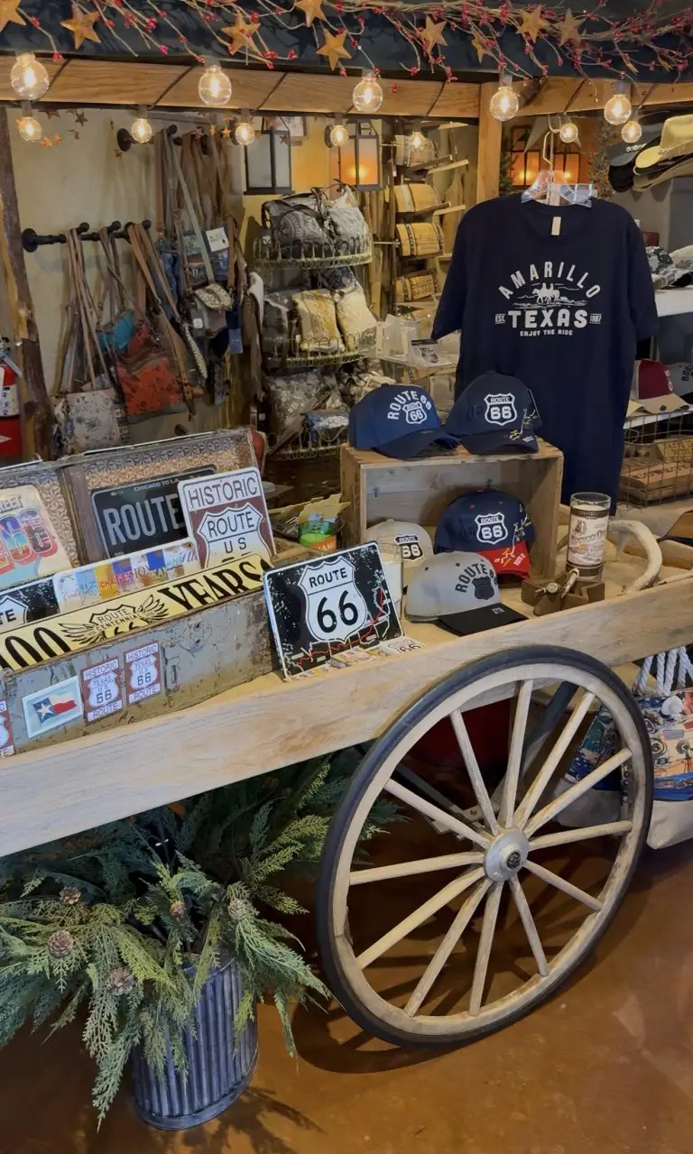 Rustic Route 66 display inside Lizzie Mae’s Mercantile in Amarillo, Texas, featuring vintage wagon décor, Route 66 signs, Amarillo Texas apparel, hats, handbags, and western-style gifts under warm string lights.